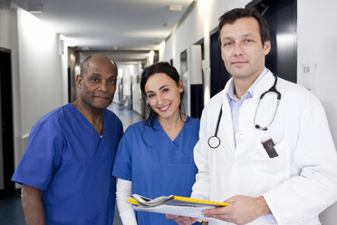 Zwei Ärzte in Kitteln und ein Arzt im Laborkittel in einem Krankenhausflur - FSIF00342