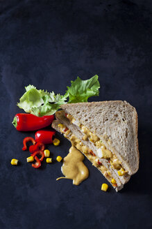 Hähnchensandwich mit Mais, Peperoni und Currysauce auf dunklem Boden - CSF28895