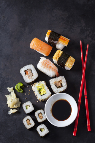 Sushi-Variationen mit Wasabi, Ingwer und einer Schale Sojasauce auf dunklem Grund, lizenzfreies Stockfoto