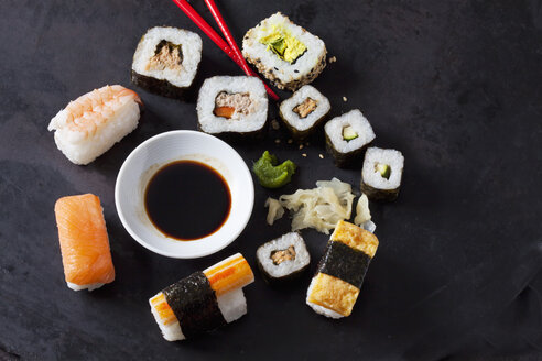 Sushi-Variationen mit Wasabi, Ingwer und einer Schale Sojasauce auf dunklem Grund - CSF28919