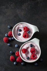 Two bowls of fruit yoghurt with blueberries and raspberries on dark ground - CSF28920