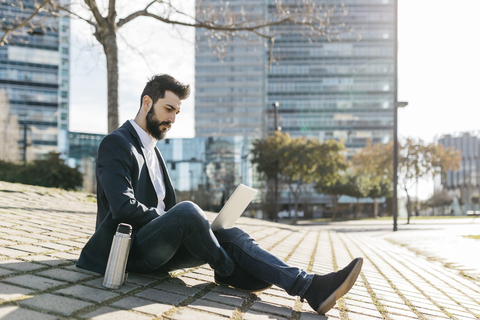 Businessman using laptop outside office building stock photo