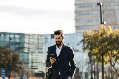 Businessman using cell phone outside office building stock photo