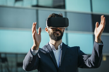 Geschäftsmann mit Virtual-Reality-Brille vor einem Bürogebäude - JRFF01550