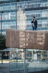 Businessman on cell phone outside office building - JRFF01556