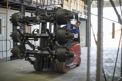 Worker moving equipment riding forklift stock photo