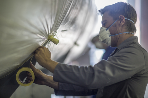 Worker in a factory wearing dust mask taping stock photo