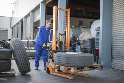 Worker moving a tire using a mobile forklift stock photo