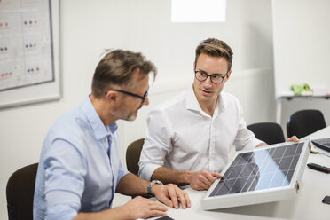 Two businessmen examining solar panel on desk in office - DIGF03292