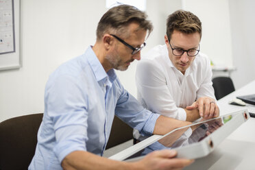 Two businessmen examining solar panel on desk in office - DIGF03293