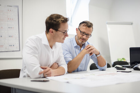 Zwei Geschäftsleute besprechen einen Plan auf einem Schreibtisch im Büro - DIGF03297