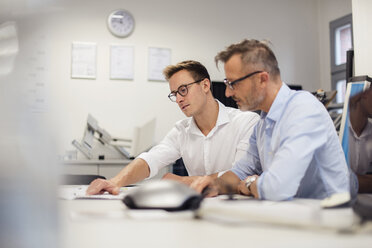 Zwei Geschäftsleute besprechen einen Plan auf einem Schreibtisch im Büro - DIGF03298