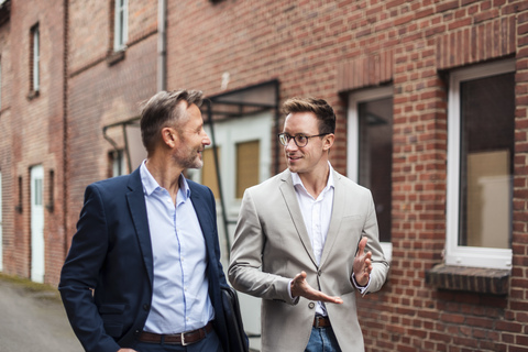 Two businessmen talking at brick building stock photo