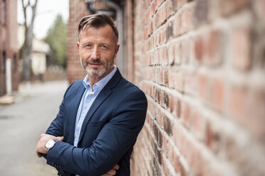 Portrait of confident mature businessman at brick wall - DIGF03310