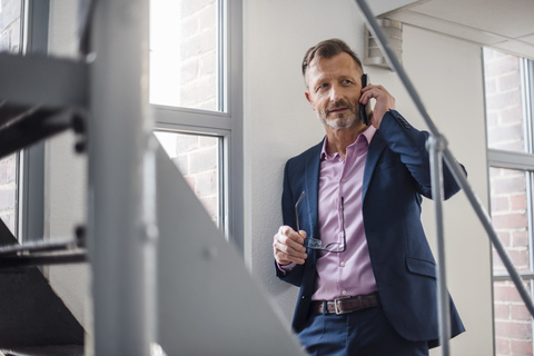 Mature businessman on cell phone at the window stock photo