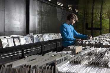 Ein junger Mann sucht in einem Plattenladen nach Schallplatten - FSIF00361