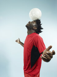 A young man balancing a soccer ball on her forehead - FSIF00407