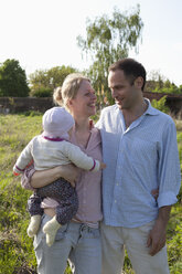 A man and a woman holding a baby standing in their backyard - FSIF00442