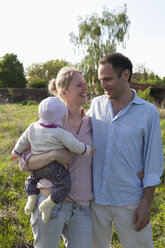 Ein Mann und eine Frau mit einem Baby im Arm stehen in ihrem Hinterhof - FSIF00442