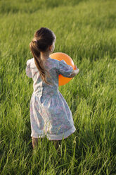 Rückansicht eines Mädchens, das einen Luftballon in einem Feld hält - FSIF00448