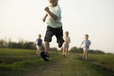 Tiefblick auf einen Jungen, der auf einem Feld rennt, mit anderen Kindern dahinter - FSIF00458