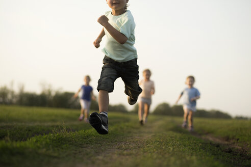 Low view of a boy running in a field with other children behind - FSIF00458