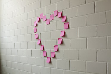 Leere Haftnotizen in Form eines Herzens auf einer Backsteinmauer angeordnet - FSIF00464