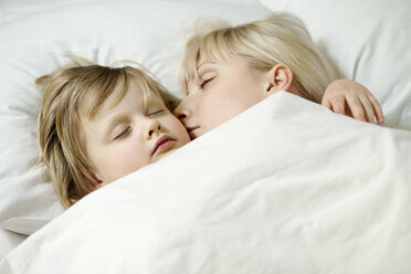 Eine Mutter und ihre kleine Tochter schlafen Seite an Seite in einem Bett - FSIF00468