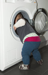 Ein kleiner Junge greift in eine Waschmaschine - FSIF00510
