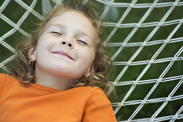 Ein junges lächelndes Mädchen liegt mit geschlossenen Augen in einer Hängematte - FSIF00518