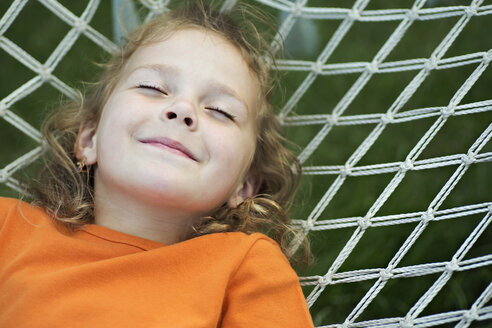 A young smiling girl lying on a hammock with her eyes closed - FSIF00518