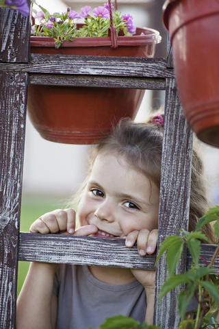 Ein junges lächelndes Mädchen schaut durch ein Spalier, lizenzfreies Stockfoto