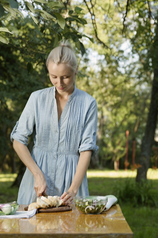 Eine Frau bereitet im Garten eine gesunde Mahlzeit zu, lizenzfreies Stockfoto