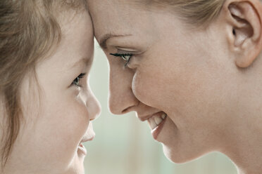 A smiling mother and daughter touching foreheads, close-up - FSIF00530