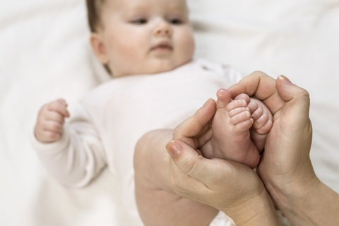 Mutter hält die Füße des Kindes, lizenzfreies Stockfoto