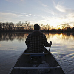 A man in a canoe on a lake at sunset, rear view - FSIF00574