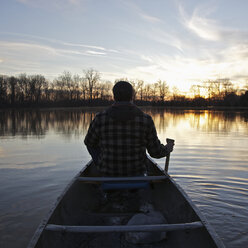 Ein Mann in einem Kanu auf einem See bei Sonnenuntergang, Rückansicht - FSIF00574