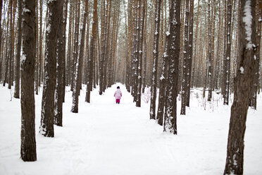 Ein junges Mädchen, das einen schneebedeckten Pfad im Wald hinuntergeht - FSIF00604
