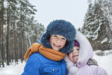 A cheerful brother and sister in warm winter clothing outdoors in winter - FSIF00605