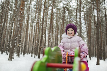 A young cheerful girl on a piece of playground equipment in winter - FSIF00609