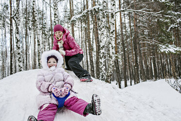 A young girl sledding while her mother looks on - FSIF00610