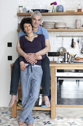 Ein liebevoll lächelndes Paar gemischten Alters in ihrer Küche - FSIF00625