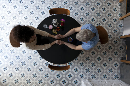 A mixed age couple holding hands at the breakfast table, directly above - FSIF00626