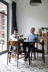Ein fröhliches, hippes, altersgemischtes Paar frühstückt gemeinsam in seinem Esszimmer - FSIF00627