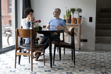 A cheerful hip mixed age couple enjoying breakfast together in their dining room - FSIF00628