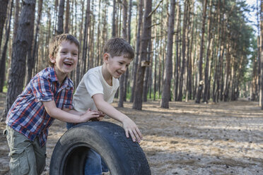 Zwei Jungen schieben einen Reifen in einem Waldgebiet - FSIF00693