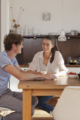 Young couple sitting at dining table in kitchen - FSIF00714