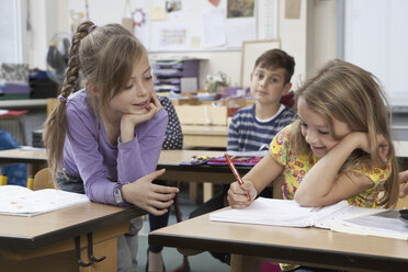 Students writing on book in classroom - FSIF00737