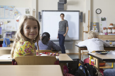 Mädchen sitzt im Klassenzimmer und lächelt - FSIF00741