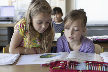 Mädchen lesen ein Buch im Klassenzimmer - FSIF00747